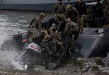 Ein Combatant Craft Medium der U.S. Navy nimmt SEALs mit einem Schlauchboot auf.