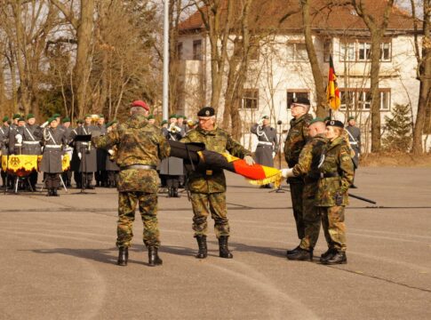 Generalleutnant Alfons Mais (l.) und Generalmajor Andreas Henne (m.) entrollten die neue Truppenfahne der Heimatschutzdivision.