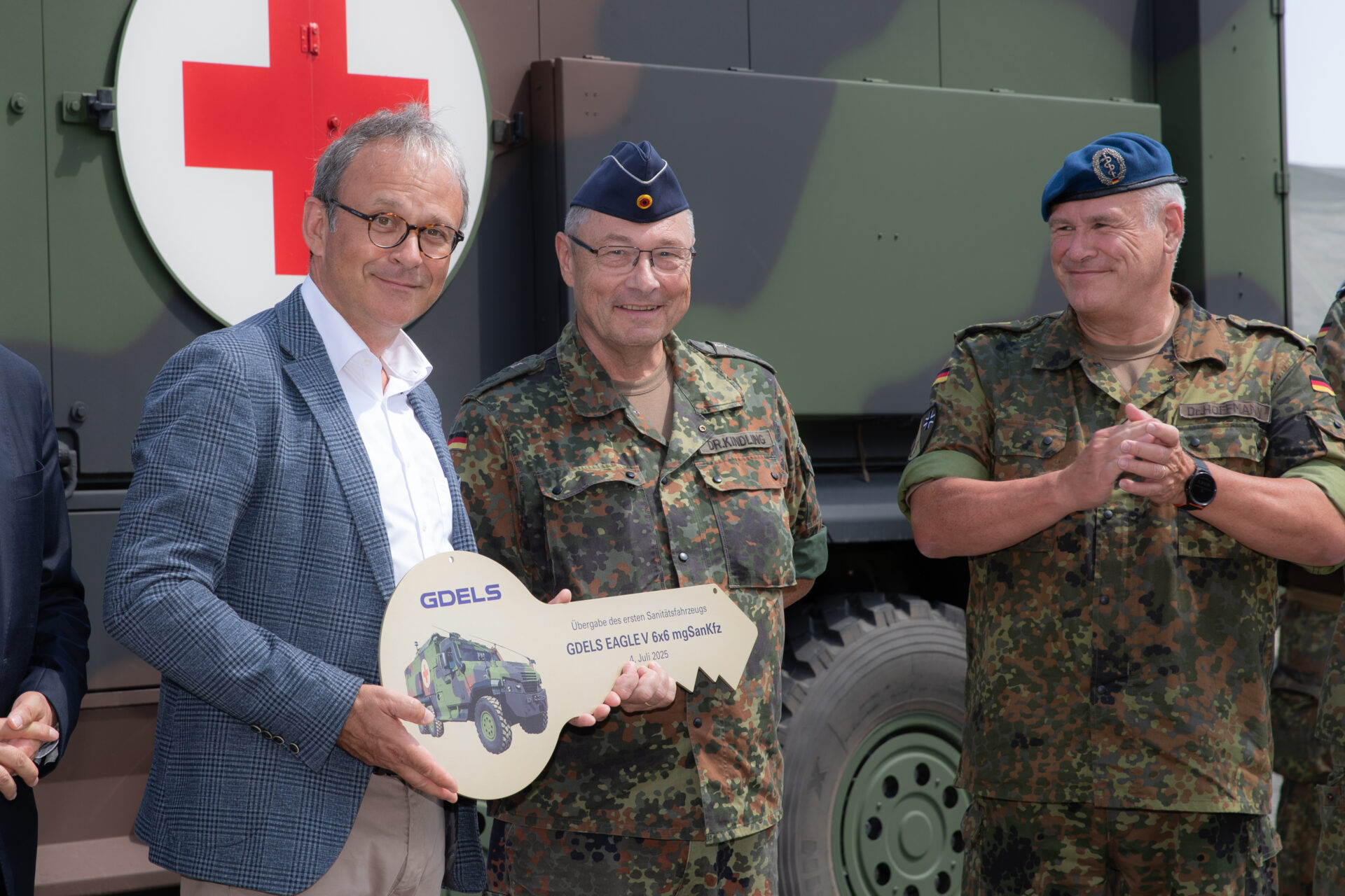 Fähigkeitslücke geschlossen: Sanitätskraftfahrzeug Eagle V 6x6 übergeben 4 Das neue mittlere geschützte Sanitätskraftfahrzeug EAGLE V 6x6 mgSanKfz wurde während der Informations- und Lehrübung des Sanitätsdienstes der Bundeswehr 2025 in Feldkirchen, vom Hersteller General Dynamics European Landsystems (GDELS) durch Herrn Dr. Thomas Kauffmann an die Bundeswehr übergeben. Oberstapotheker Dr. Ullrich Kindling vom Bundesamt für Ausrüstung, Informationstechnik und Nutzung der Bundeswehr (BAAINBw) gab den symbolischen Schlüssel an Herrn Generaloberstabsarzt Dr. Ralf Hoffmann, Befehlshaber des Zentralen Sanitätsdienstes der Bundeswehr weiter, so dass zum Abschluss der Fahrzeugschlüssel an den militärischen Kraftfahrer und Kommandanten des neuen EAGLE V 6x6 mgSanKfz durch Herrn Generalsstabsarzt Dr. Johannes Backus und Oberstarzt Dr. Melanie Heyde übergeben werden konnte. Foto © Bundeswehr/Patrick Grüterich)