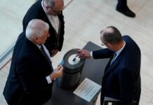 Bundeskanzler Friedrich Merz (r.) gibt bei der namentlichen Abstimmung über das Gesetz für einen neuen Wehrdienst seine Stimmkarte im Bundestag ab.