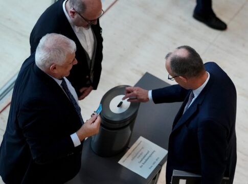 Bundeskanzler Friedrich Merz (r.) gibt bei der namentlichen Abstimmung über das Gesetz für einen neuen Wehrdienst seine Stimmkarte im Bundestag ab.
