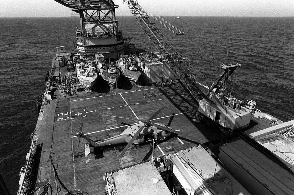 Drei Patrouillenboote Mark III und ein UH-60 Black Hawk der U.S. Army an Bord der schwimmenden Operationsbasis Hercules. 