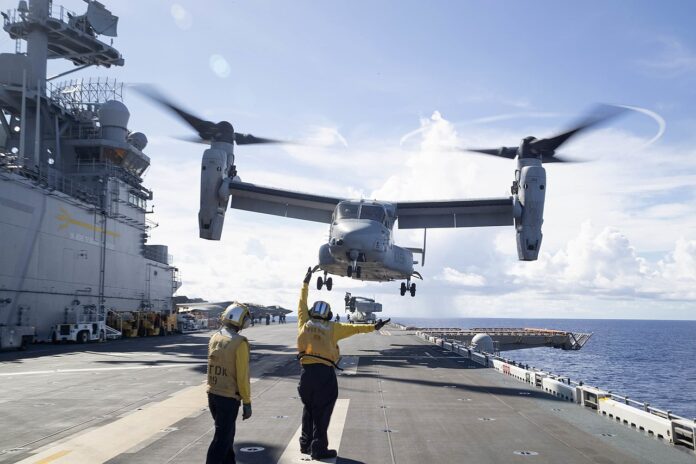 Ein MV-22 Osprey Kipprotorflugzeug des U.S. Marine Corps (USMC) über dem Amphibienträger USS Tripoli.