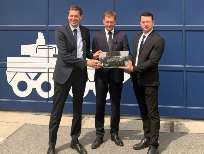 Zum einjährigen Bestehen des KNDS-Standorts in Görlitz überreichten CEO Florian Hohenwarter (l.) und Standortleiter Enrico Blocksdorf (r.) Sachsens Ministerpräsident Michael Kretschmer das Modell eines Boxers, für den hier Module und künftig auch Wannen produziert werden.